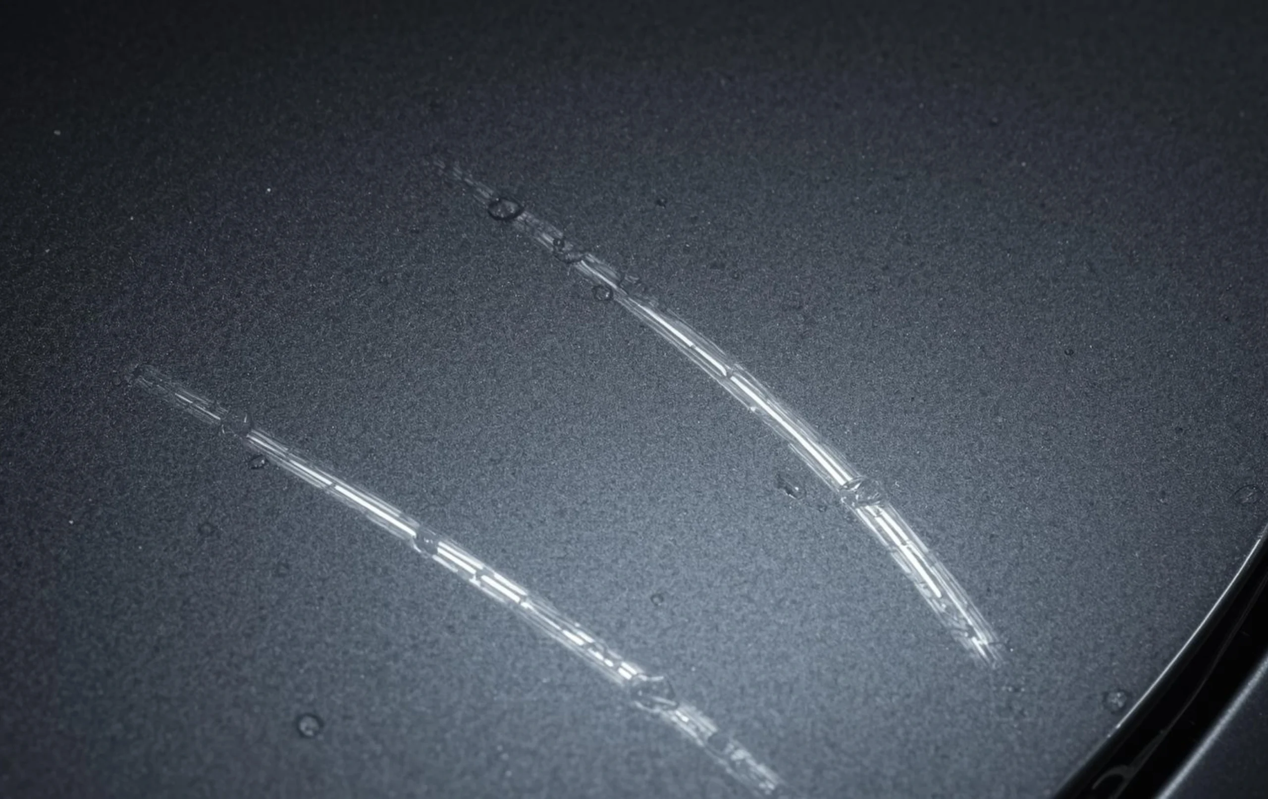 Close-up of swirl marks and light scratches on car bonnet paint surface